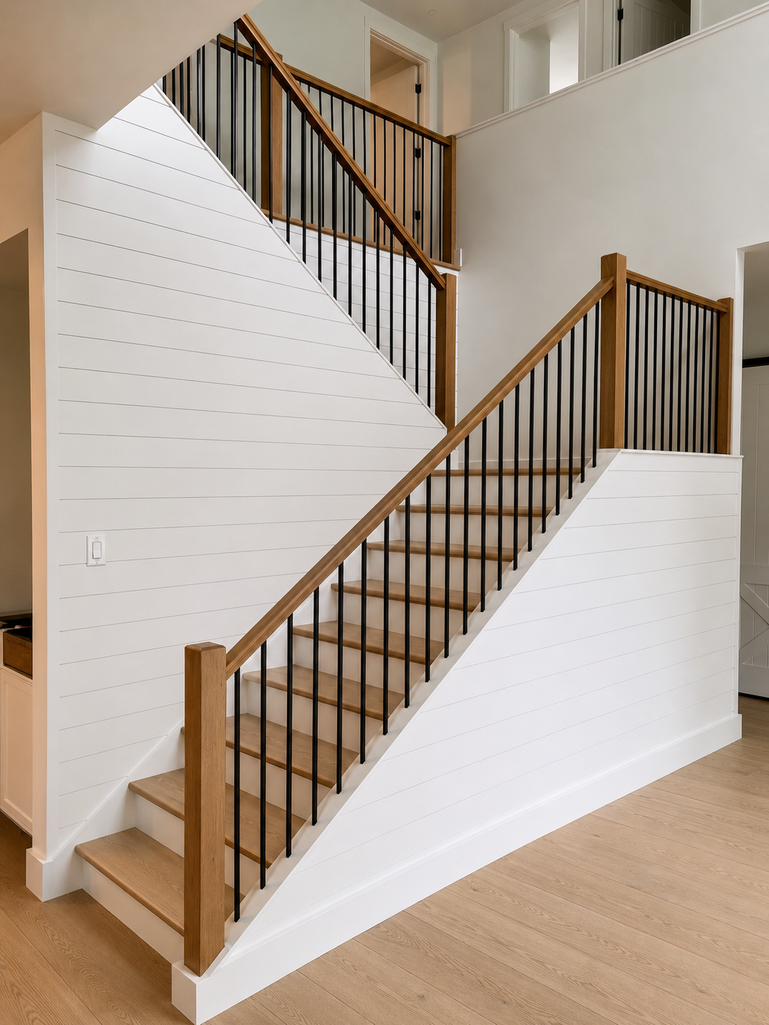 Modern white oak staircase with black metal balusters and wood handrail